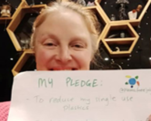 Close up image of Kathryn Mistica holding up a piece of paper showing her pledge to sustainability