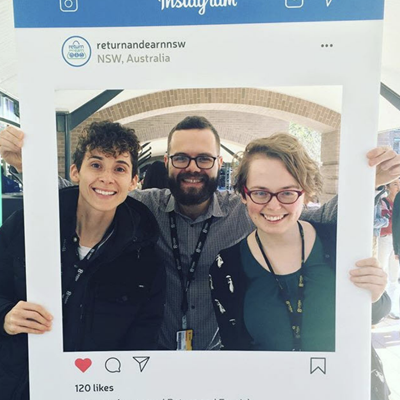 Image of Daniel holding up a Instagram cut out with two other people