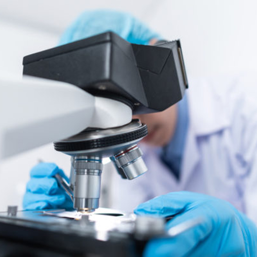 Image of a person who is out of focus and working with a microscope.