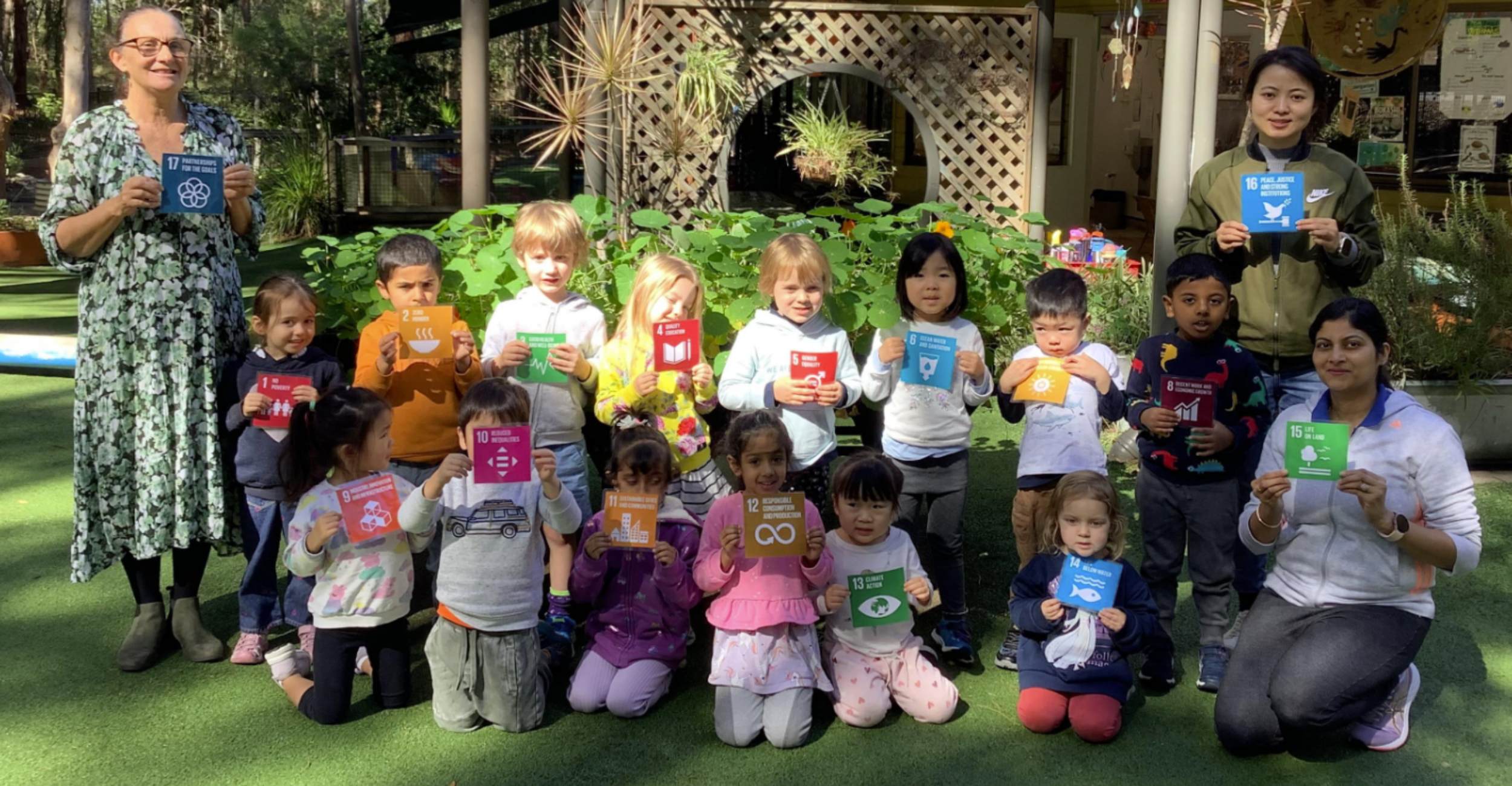 This image shows a group of early childhood attendees holding SDG banners